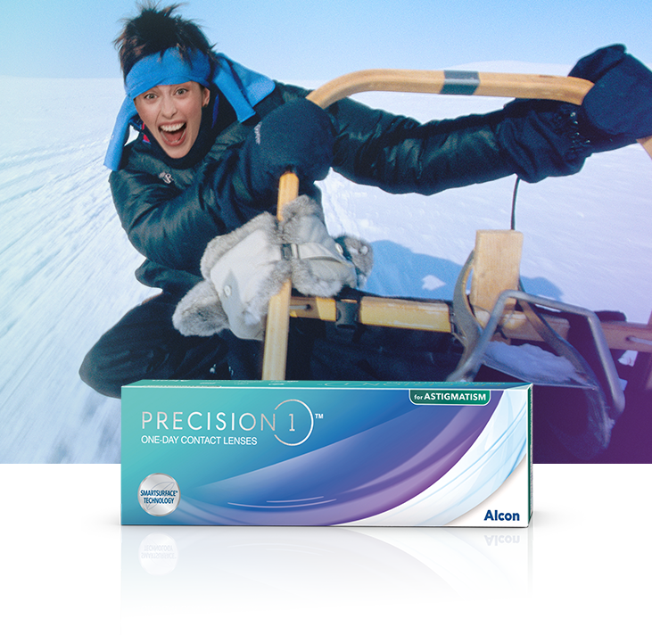Woman on snow sledding with Precision1 for Astigmatism contact lenses product box in foreground