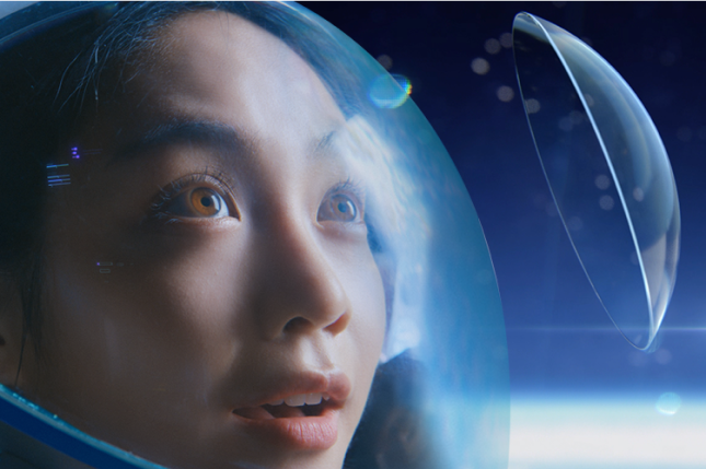 Woman wearing astronaut helmet looking at a floating contact lens