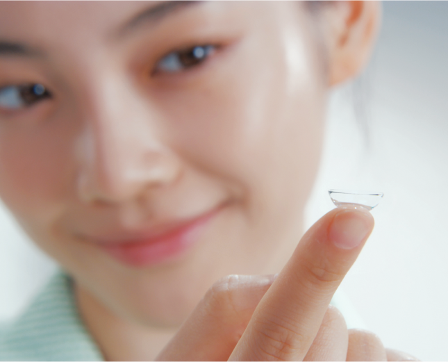 Young woman balancing contact lens on finger tip while smiling