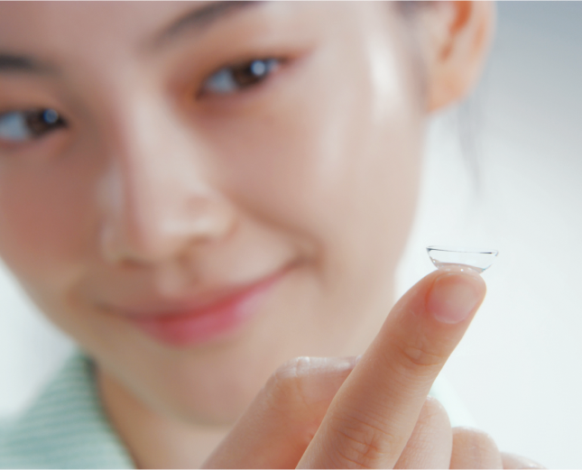 young woman balancing contact lens on finger tip while smiling