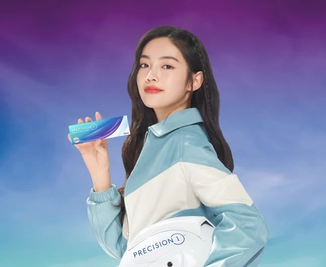 young woman wearing a light blue and white leather jacket holding a box of Precision1 one-day contact lenses