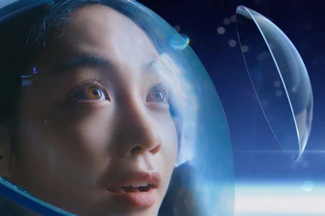 Woman wearing astronaut helmet looking at a floating contact lens